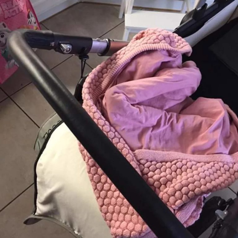 Kundenfoto: schwarzer Schiebebügelbezug aus Leder an einem Kinderwagen mit rosa Decke